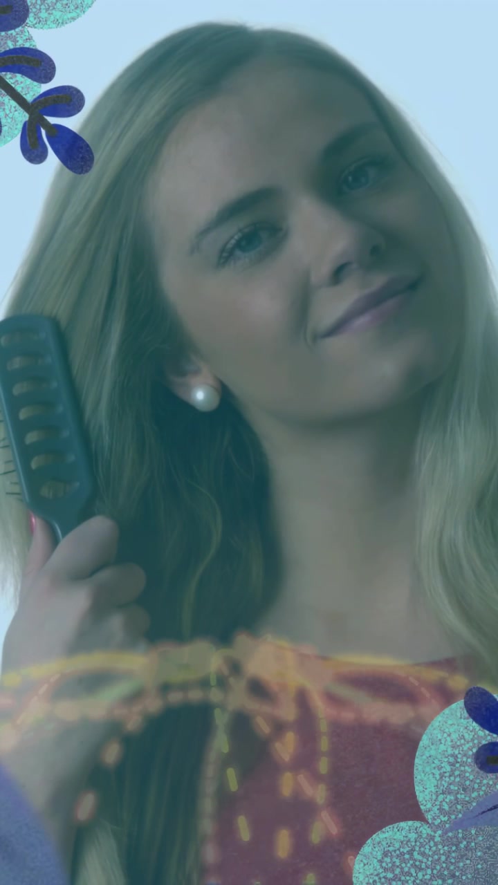 Video vertical: Mujer sosteniendo un cepillo cerca de la oreja, cepillándose el cabello para belleza, con superposiciones florales enmarcando el rostro.