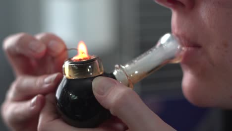 woman lighting and smoking medical marijuana through a pipe