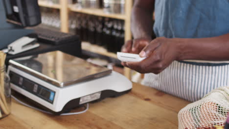 customer making contactless payment for shopping at checkout of grocery store using mobile phone