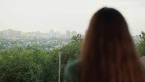 la mujer disfruta del paisaje urbano bajo el cielo gris. la dama morena realiza un estado de ánimo pensativo contra la gran ciudad en un clima desagradable. emociones melancólicas en la temporada de lluvias