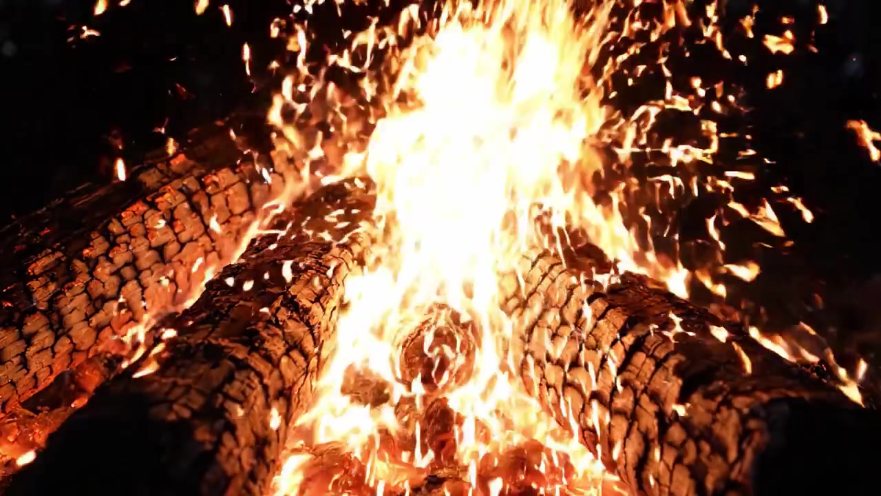 Captivating Flames Dance Around Charred Logs in a Campfire Setting, Illuminating the Night with Warmth and Energy, Creating a Relaxing Ambience for Gatherings