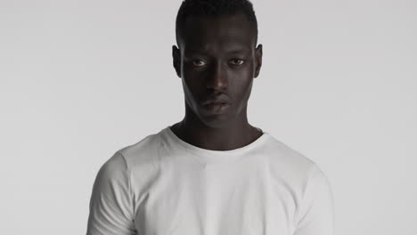 un hombre afroamericano serio con un fondo gris.
