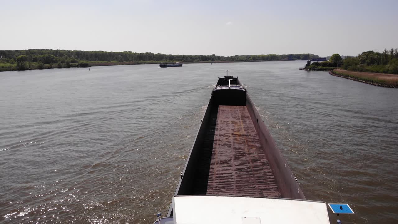 cubierta de almacenamiento vacante de una barcaza que navega en un río tranquilo durante la mañana soleada