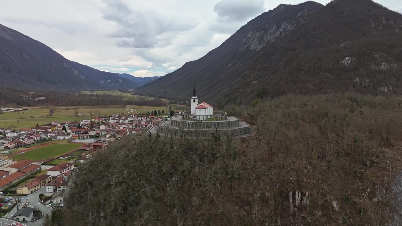 Kobarid, Slovenia, Sacrario militare di Caporetto, monumento ai caduti e ossario su una collina boscosa nella valle dell'Isonzo con il paesaggio delle Alpi Giulie, visto con drone