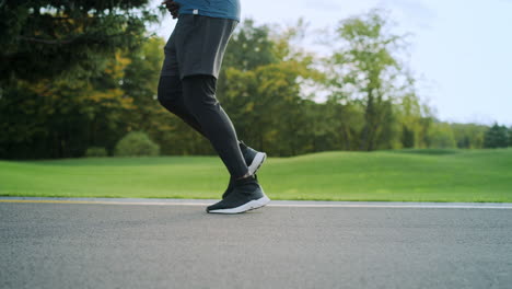 atleta con zapatos deportivos corriendo por la carretera