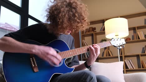 a young curly red-haired guy is learning to play the guitar. a talented guitarist plays a calm melody. hobby