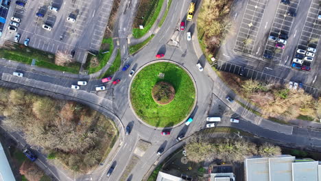 Aerial-birds-eye-view-shot-rotating-with-car-traffic-around-large-busy-UK-roundabout-4K