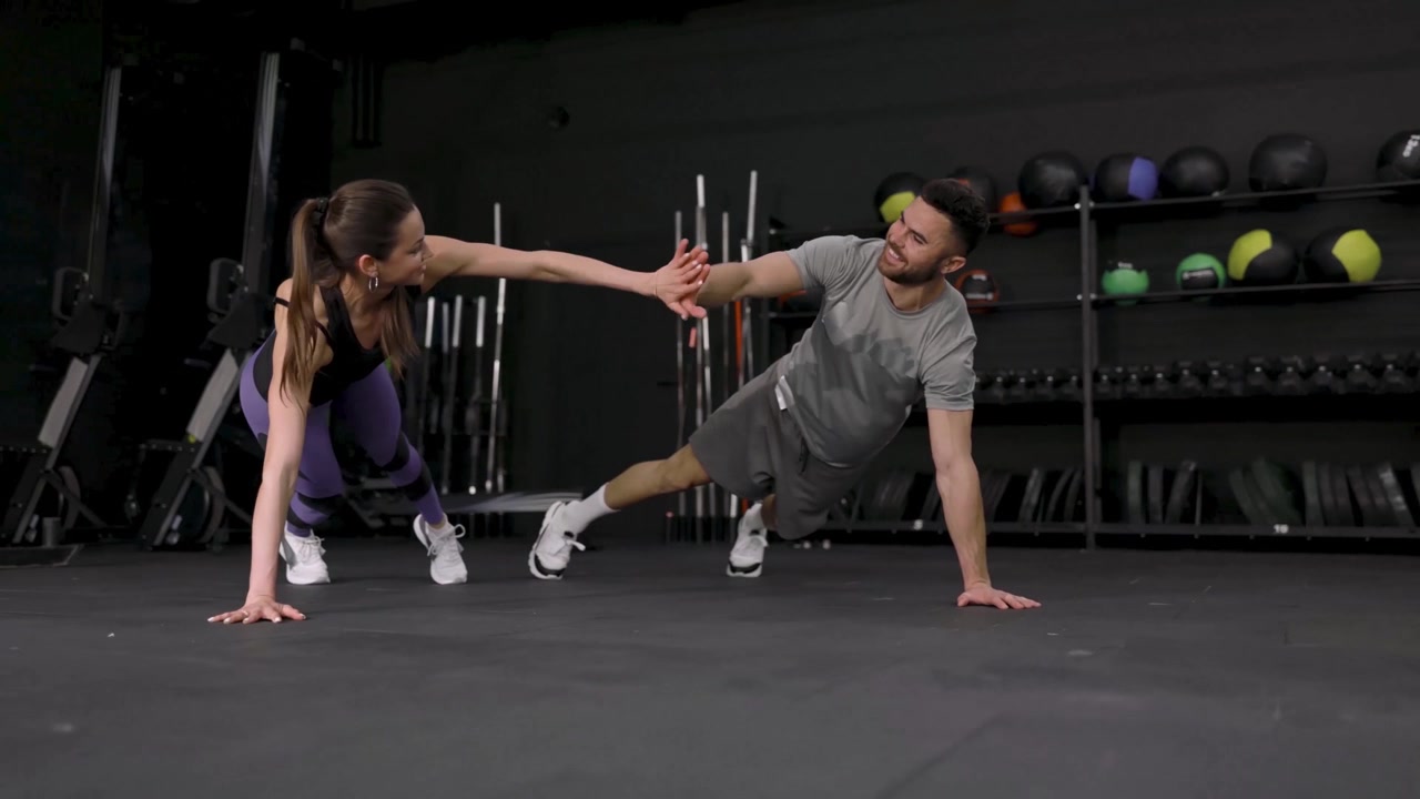 Pareja en forma haciendo flexiones y chocando las cinco durante el entrenamiento