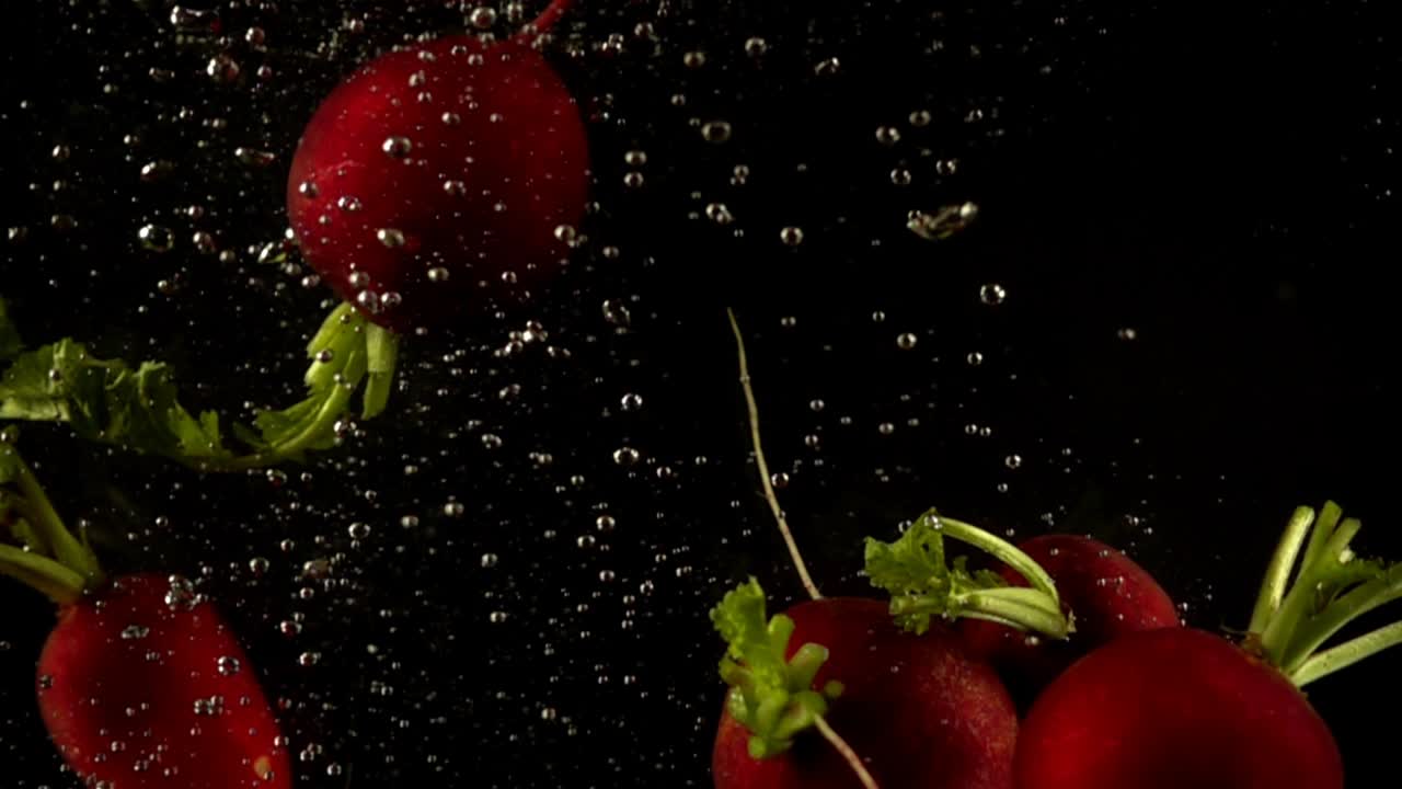 Falling of a radish in water. Slow motion. Black background