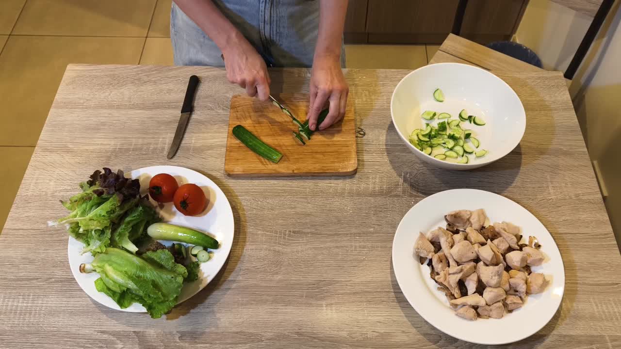 Preparing a fresh salad with cucumber, tomato, and chicken