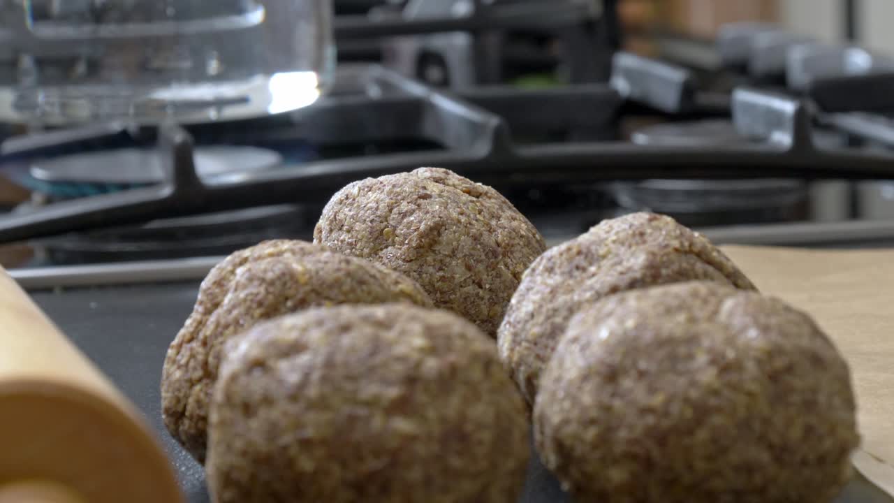 Balls of flaxseed dough sit prepared on a counter with boiling water in the background