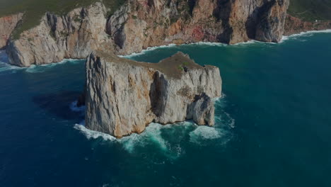 Aerial-view-in-a-circle-of-Pan-di-Zucchero-on-the-island-of-Sardinia-and-where-you-can-see-the-waves-impacting-the-rock,-near-Masua