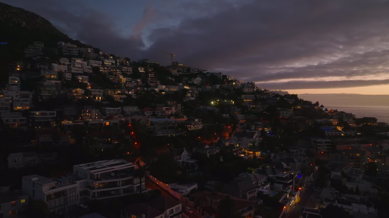 어두워지는 해변 에 있는 고급스러운 부동산 들 의 슬라이드 와 판  ⁇ . 색채 있는 황혼 하늘 을 반영 하는 창문 들. 케이프 타운, 남아프리카