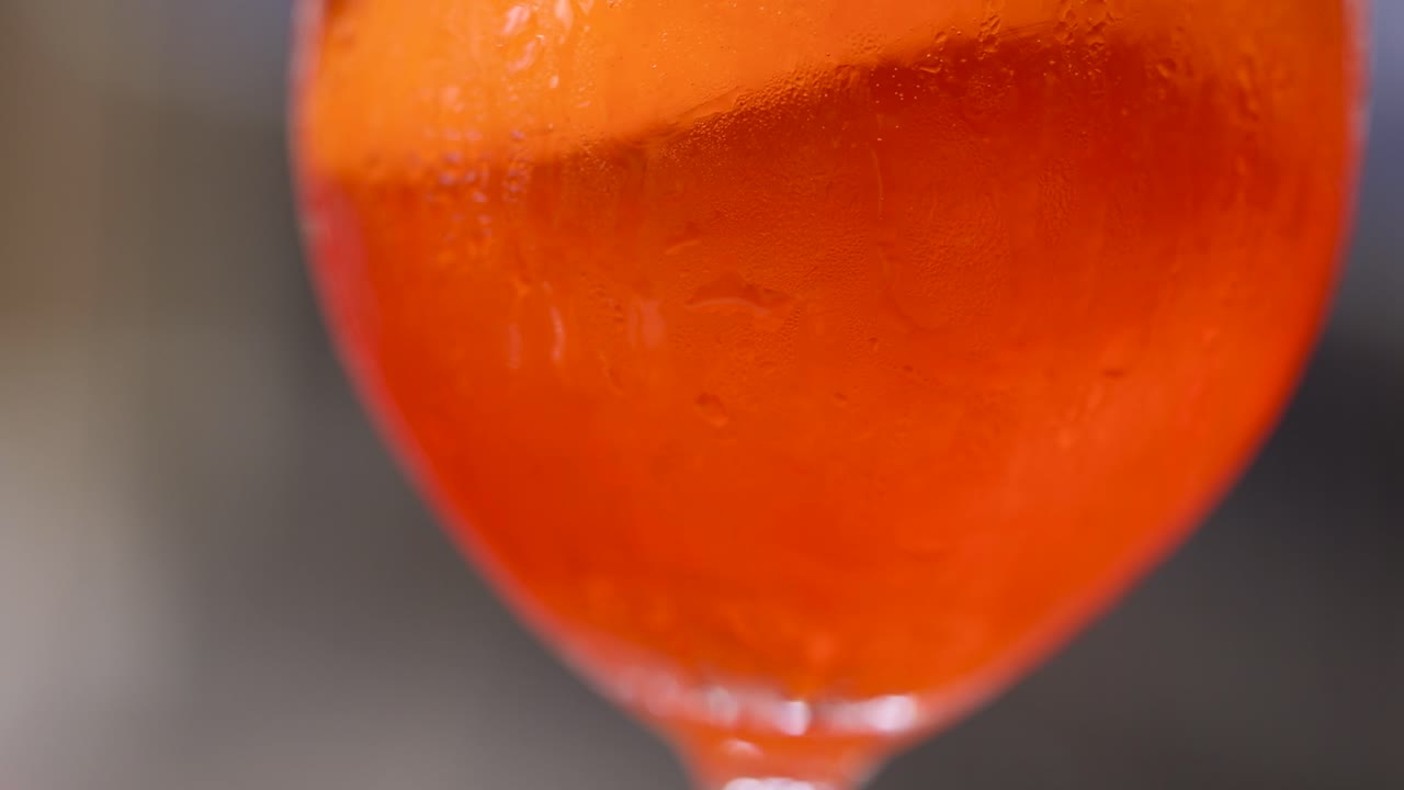 Primo piano di un vivace cocktail Negroni arancione mescolato con cannuccia