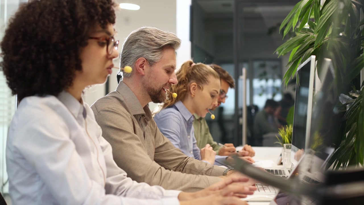 Operatori di call center diversificati che lavorano su portatili in un ufficio moderno