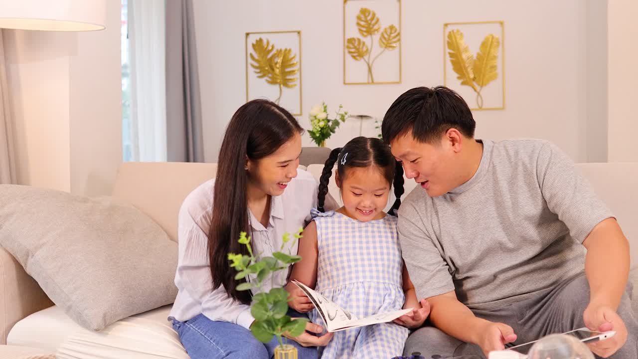 Parents and daughter read a book together on a bright, modern sofa with natural lighting