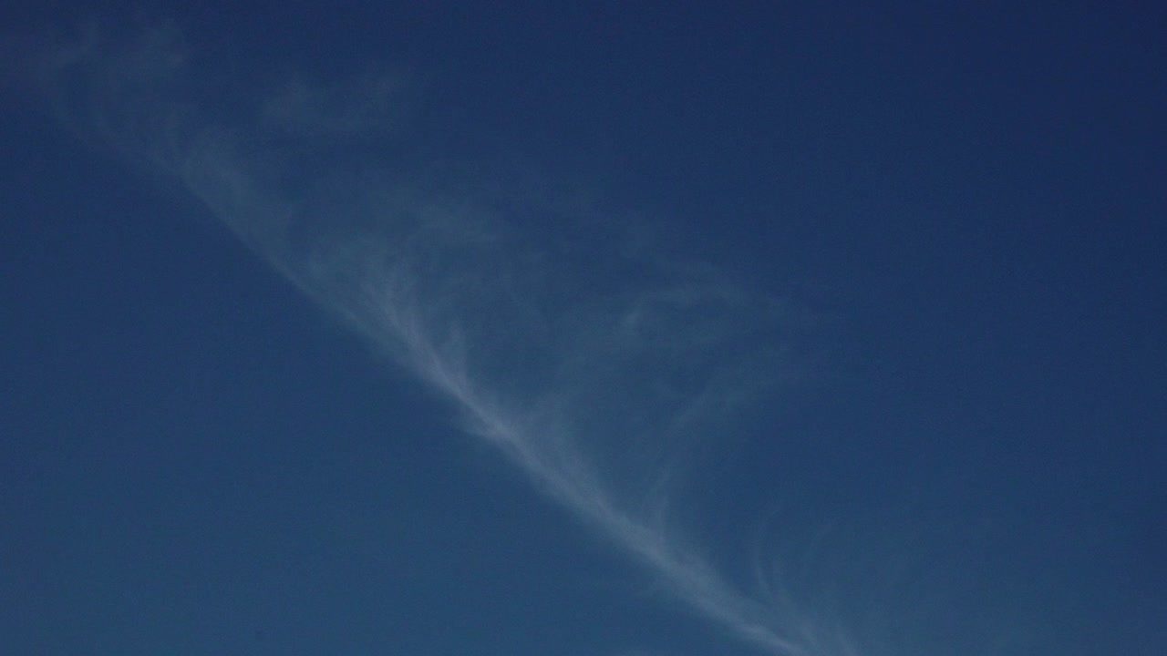 비행기 의 콘트레일 은 은 파란 하늘 을 가로질러 대각선 으로 달려 가며, 색 의 증기 줄무 를 남기고 있다