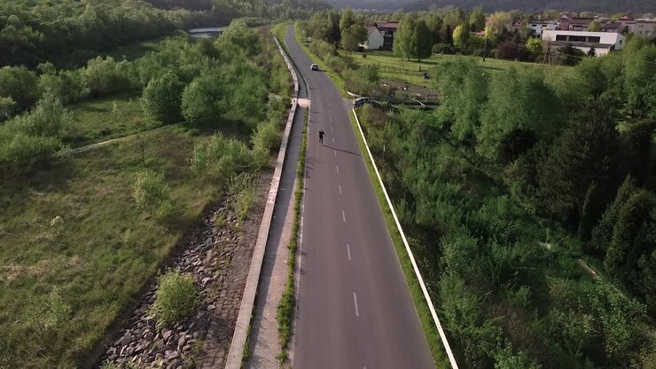 uomo che pattina a rotelle sulla strada vuota nella ripresa aerea di una giornata di sole