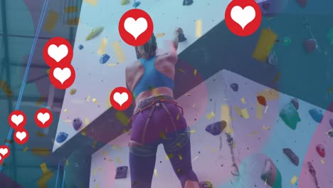 Multiple-heart-icons-floating-against-caucasian-fit-woman-wall-climbing-at-the-gym