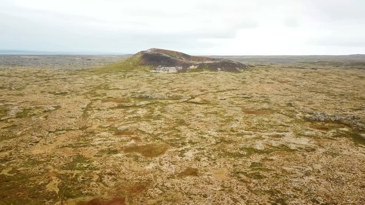 The Saxholl volcanic crater in Iceland rises from a vast, barren landscape, marked by rugged terrain and sparse vegetation. Natural setting features volcanic textures and unique geological patterns