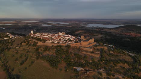 drone volando sobre el pueblo de monsaraz con el río alqueva en el fondo al atardecer, portugal