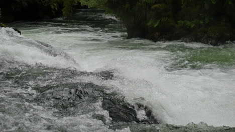 incline hacia arriba la toma de ángulo bajo de las cataratas de tutea que fluyen y salpican en nueva zelanda