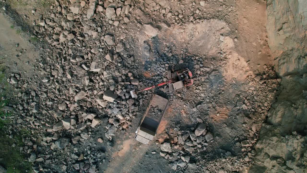 Top down aerial view of Excavators loading rocks into a portable rock crusher. Equipment for the mining industry. A small crusher works with crushed rock