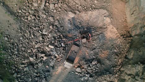 top down aerial view of excavators loading rocks into a portable rock crusher. equipment for the mining industry. a small crusher works with crushed rock