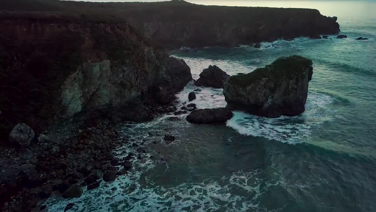 Le onde impetuose dell'Oceano Pacifico si infrangono sulla rocciosa Sand Dollar Beach al tramonto a Big Sur, California