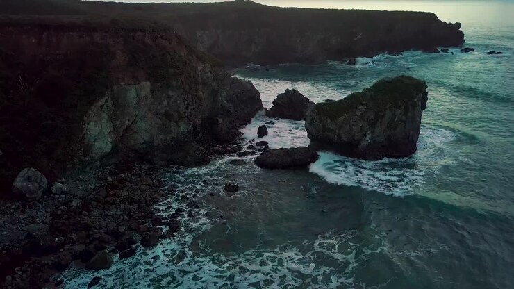 Le onde impetuose dell'Oceano Pacifico si infrangono sulla rocciosa Sand Dollar Beach al tramonto a Big Sur, California