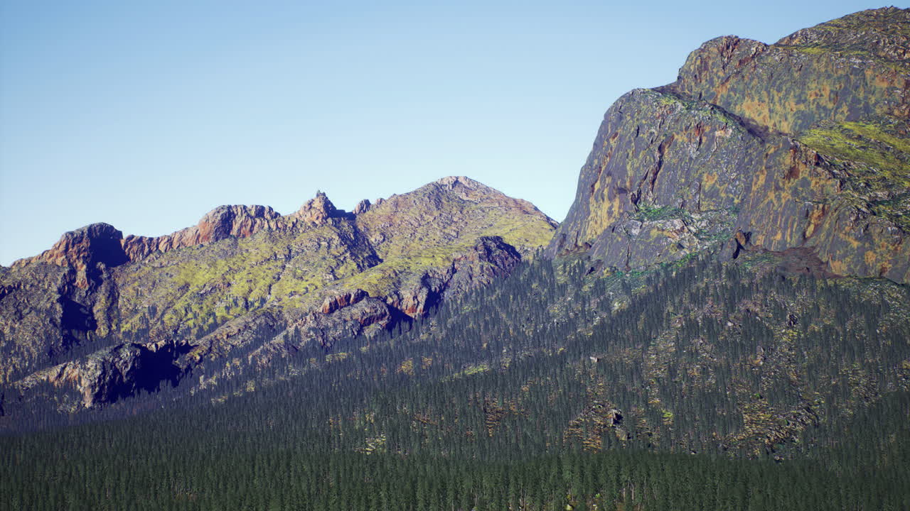 Majestic mountain range with dense forest under clear blue sky