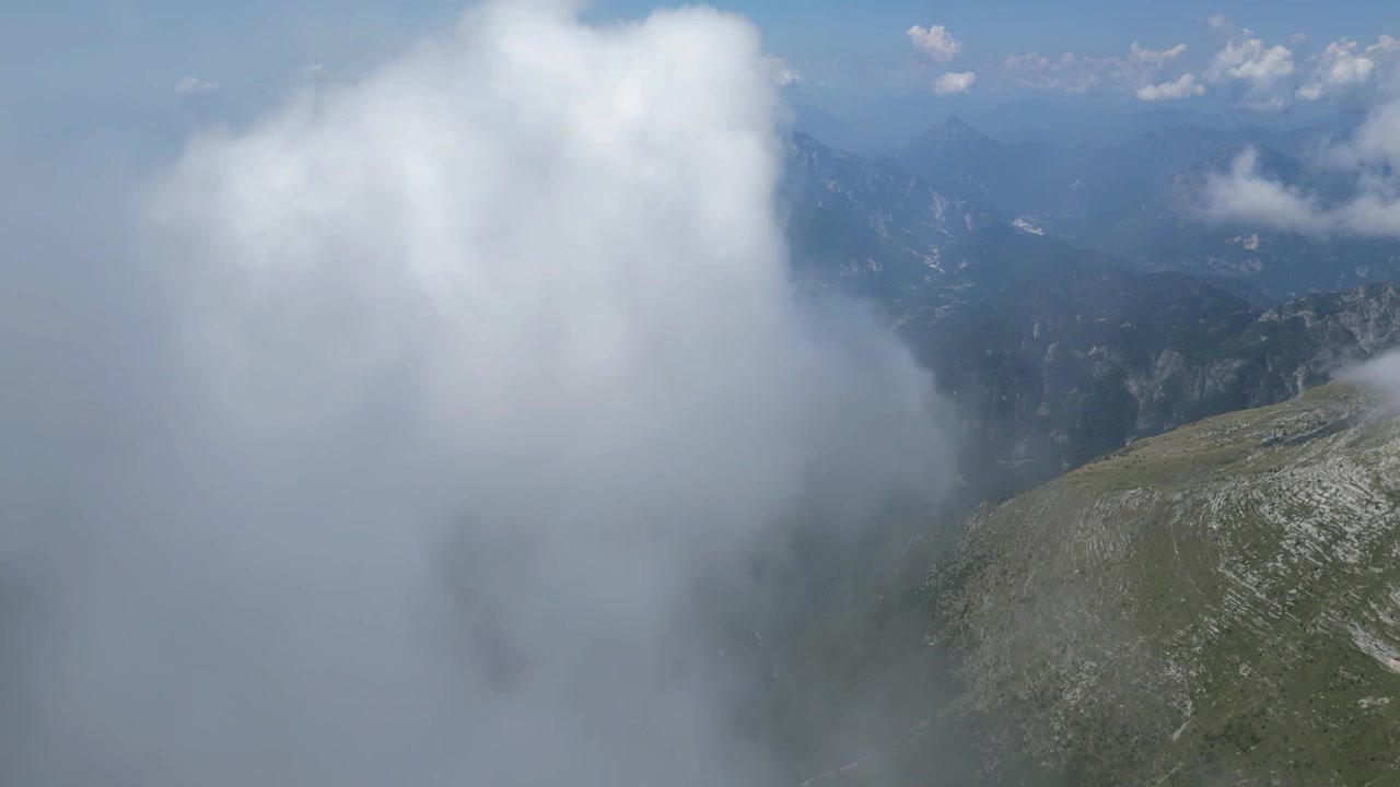 Aerial drone footage of Monte Canin in Friuli, Italy: rugged limestone peaks, rocky ridges and dramatic alpine terrain beneath a clear sky. Ideal for nature, travel and outdoor projects.