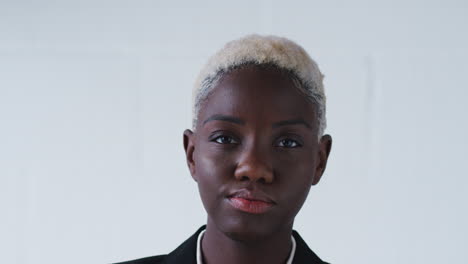 portrait of determined businesswoman in suit walking into focus against white studio wall