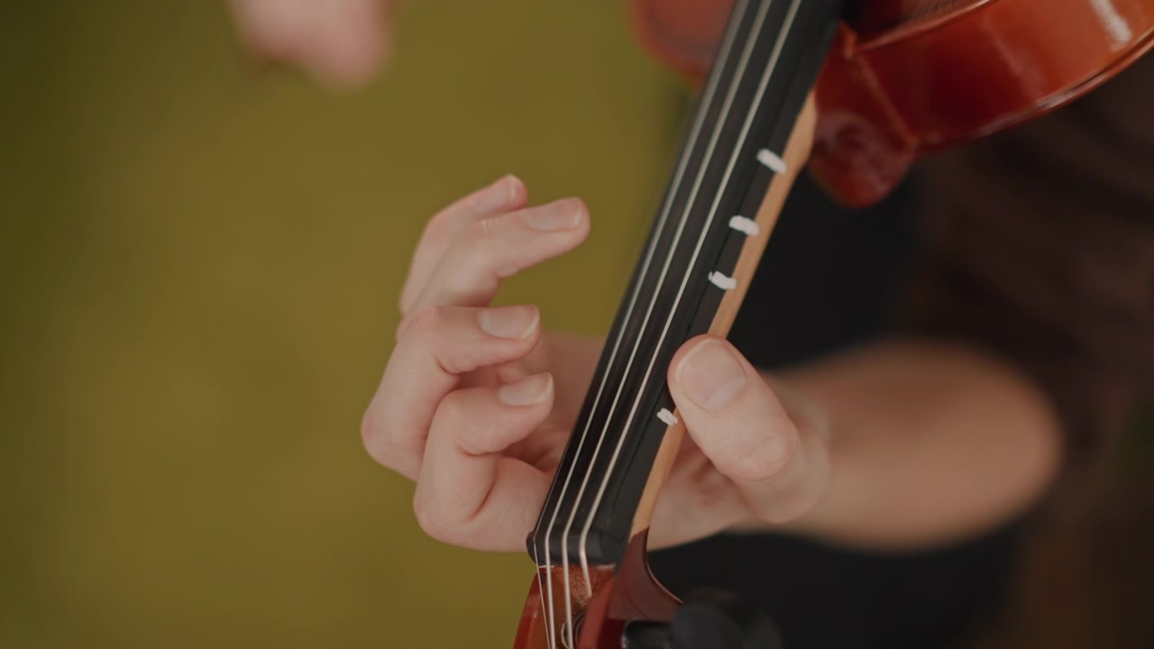 Primo piano della tastiera di un violino: l'insegnante guida le dita, lo studente riceve delicate istruzioni sulla diteggiatura, luce calda dello studio, l'insegnante regola la posizione della mano, pratica concentrata sull'intonazione e sulla diteggiatura
