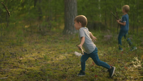a boy picks up and throws a stick in the woods in slow motion