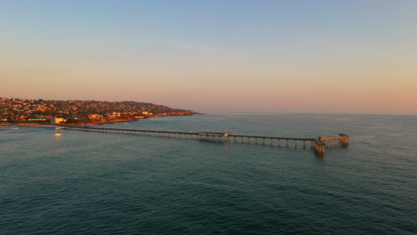 Muelle-Escénico-De-La-Playa-Del-Océano-Con-Vibrantes-Colores-De-Puesta-De-Sol-Durante-La-Hora-Dorada,-Plano-Aéreo-Ancho