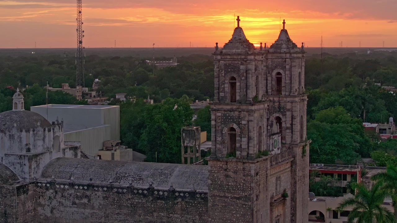 Luftaufnahme der zweitürmigen Kathedrale San Gervasio als Silhouette vor einem feurigen Sonnenuntergangshimmel in Valladolid, Yucatán, Mexiko, über der Kolonialstadt