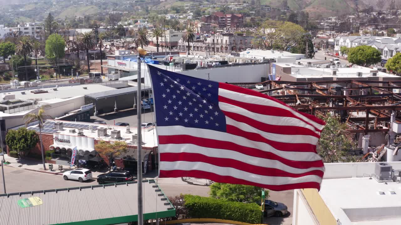 Ripresa aerea ravvicinata con pan parallax di una bandiera americana su Sunset Blvd. dopo l'incendio di Palisades a Pacific Palisades, California. 4K.