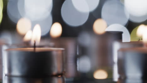 video of tea candles with white flames and copy space with bokeh on black background