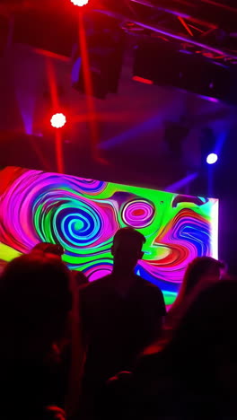colorful night club scene with vibrant lights and large screen