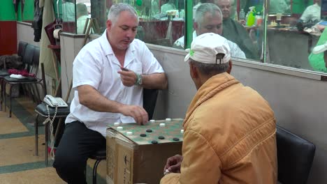 Dos-Hombres-Juegan-A-Las-Damas-En-Una-Peluquería-En-La-Habana,-Cuba