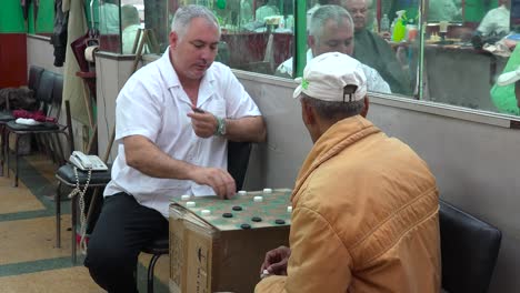 dos hombres juegan a las damas en una barbería en la habana cuba
