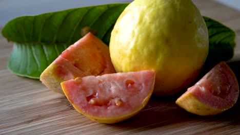 acérquese a la fruta de guayaba madura fresca entera y en rodajas con hojas en la tabla de cortar