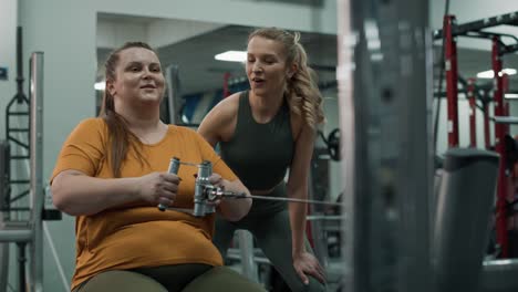 Woman-with-overweight-doing-training-with-fitness-instructor-at-the-gym.