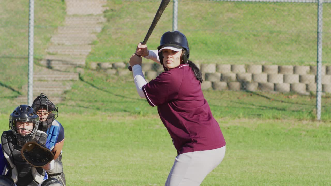 Female batter swinging bat to hit pitched ball while particle trail tracing swing in sports tech
