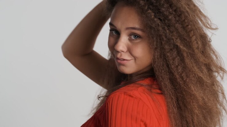 Donna riccia caucasica che sorride alla telecamera.