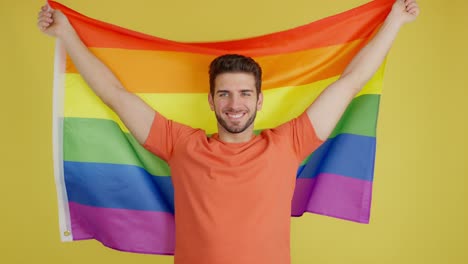 smiling man holding rainbow flag