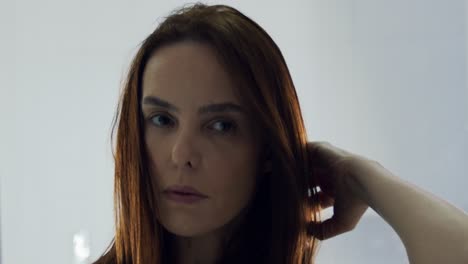 primer plano frontal de una modelo de moda mirando a la cámara después del maquillaje mientras se acaricia el pelo