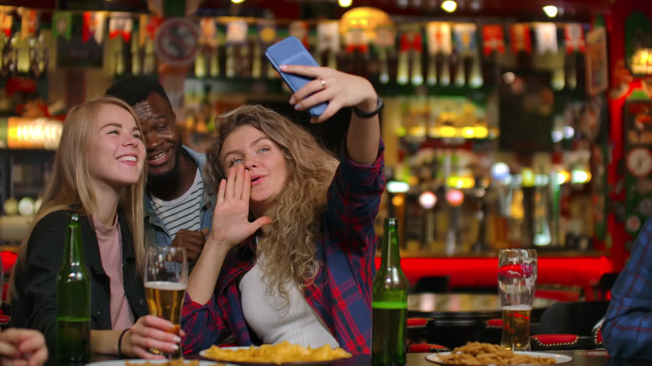 Amici che scattano foto con il telefono al bar, creano una foto condivisa sul telefono. Festa con amici al bar con birra.