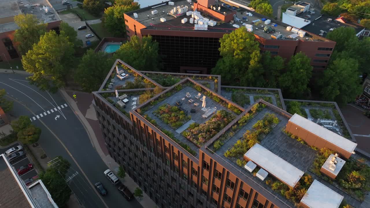 Rooftop gardens on modern urban building in downtown Charlottesville, Virginia. Multiple green spaces and seating areas. Aerial view of street and architecture below.